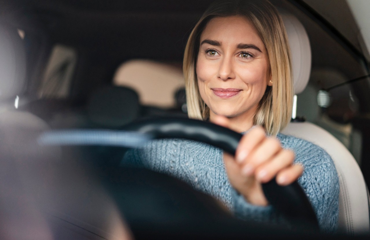Portrait of smiling young woman driving a car